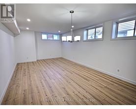 A large empty room with wooden flooring and white walls.
