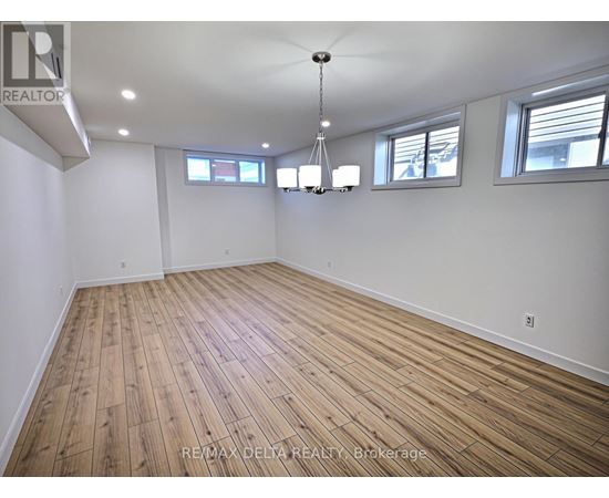 A large empty room with wooden flooring and white walls.