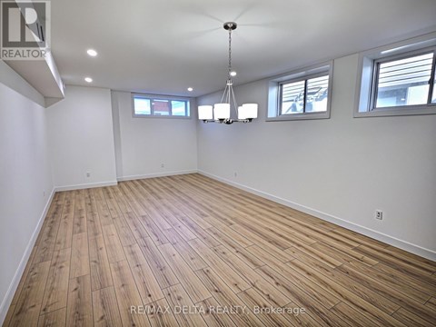 A large empty room with wooden flooring and white walls.