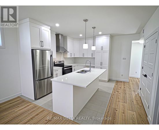 A modern kitchen with white cabinets and a wooden floor.