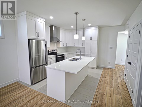 A modern kitchen with white cabinets and a wooden floor.