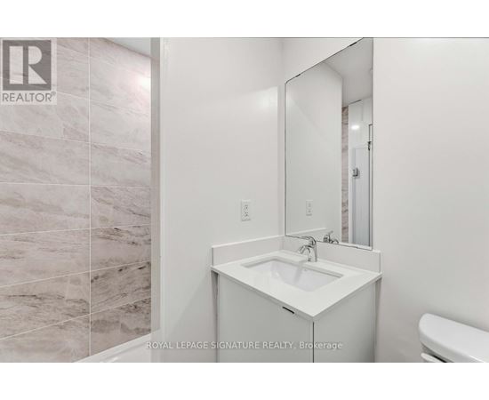 A white sink in a bathroom with a mirror above it.