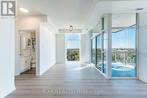 A large, empty room with a view of the pool and trees outside the window.