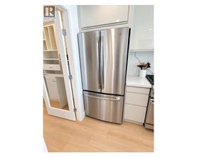 A stainless steel refrigerator is in a kitchen with a white cabinet.