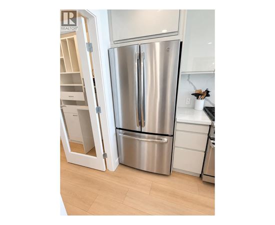 A stainless steel refrigerator is in a kitchen with a white cabinet.