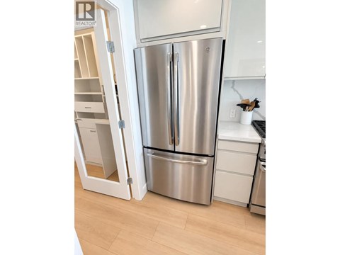 A stainless steel refrigerator is in a kitchen with a white cabinet.