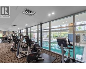 A gym with a row of treadmills and a swimming pool in the background.
