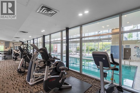 A gym with a row of treadmills and a swimming pool in the background.