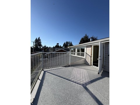 A small white building with a grey roof and a metal fence.