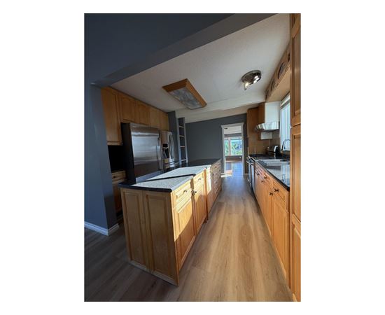 A kitchen with wooden cabinets and a stainless steel refrigerator.