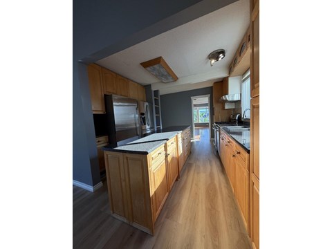 A kitchen with wooden cabinets and a stainless steel refrigerator.