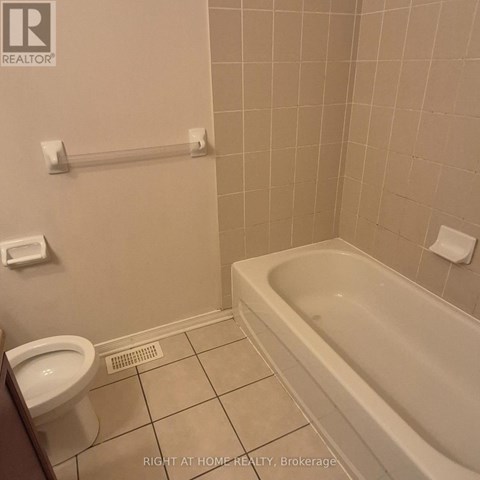 A white toilet sits next to a bathtub in a bathroom.