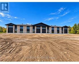 A large, unfinished building with a flat roof and multiple windows is under construction in a field.