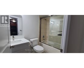 A white bathroom with a toilet, sink, and shower.