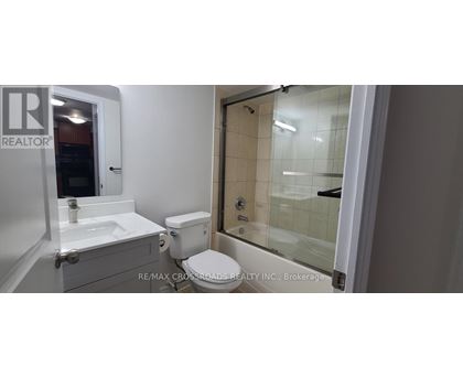 A white bathroom with a toilet, sink, and shower.