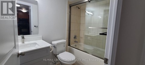A white bathroom with a toilet, sink, and shower.