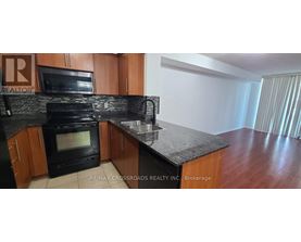 A kitchen with a black oven and brown cabinets.