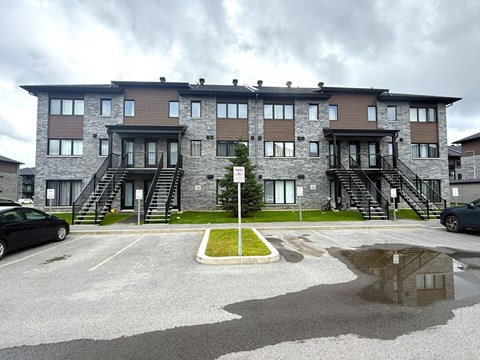 A large building with a grey and brown exterior and a small green area in front.