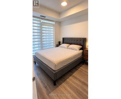A bedroom with a large bed and a window with blinds.