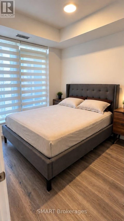 A bedroom with a large bed and a window with blinds.