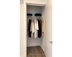 A white closet with clothes hanging on a rail.