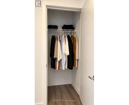 A white closet with clothes hanging on a rail.