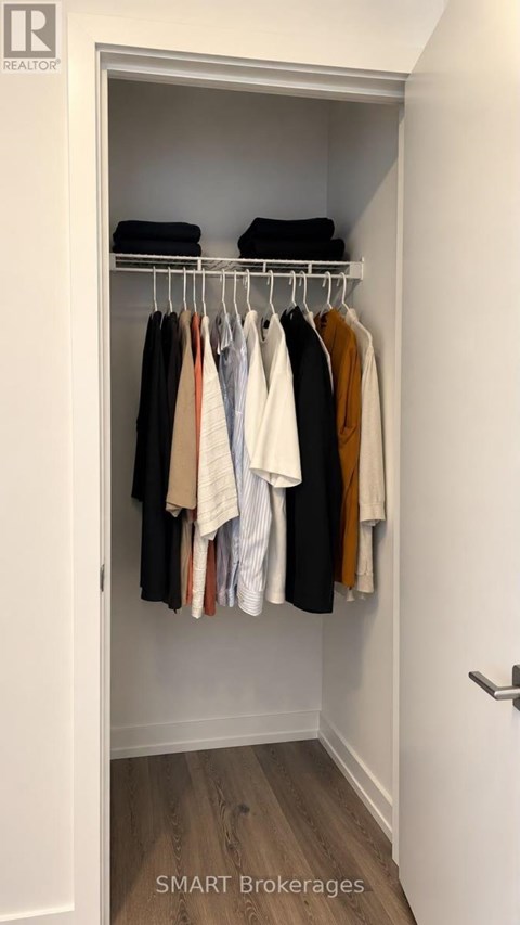 A white closet with clothes hanging on a rail.
