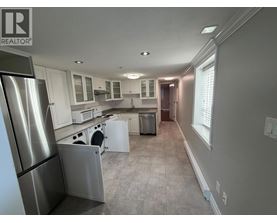 A kitchen with a refrigerator on the left and a dishwasher in the middle.