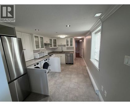 A kitchen with a refrigerator on the left and a dishwasher in the middle.