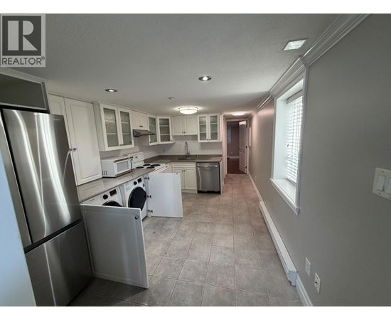 A kitchen with a refrigerator on the left and a dishwasher in the middle.