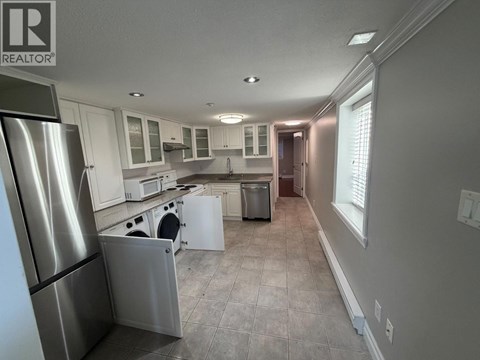 A kitchen with a refrigerator on the left and a dishwasher in the middle.