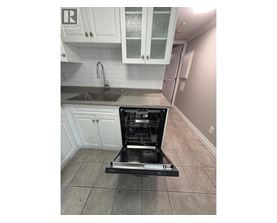 A dishwasher is placed in a kitchen with white cabinets.