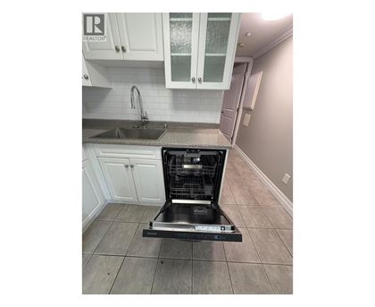 A dishwasher is placed in a kitchen with white cabinets.