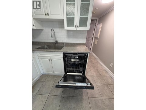 A dishwasher is placed in a kitchen with white cabinets.