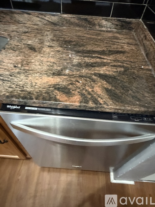 A stainless steel sink in a kitchen with a granite countertop.