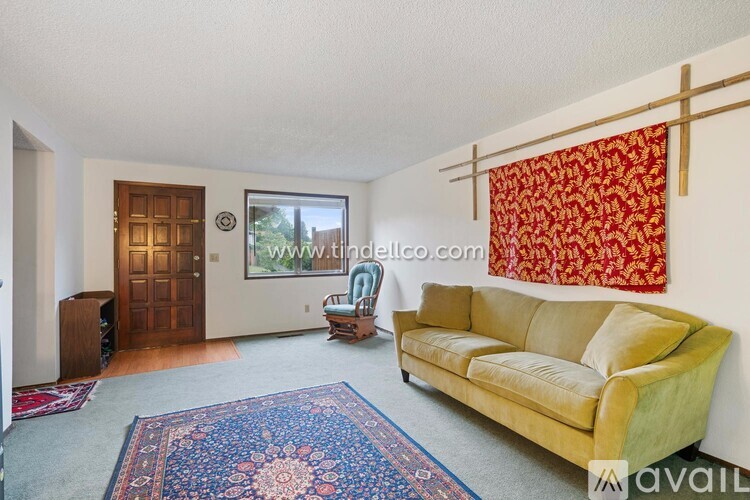 A living room with a yellow couch and a rug.