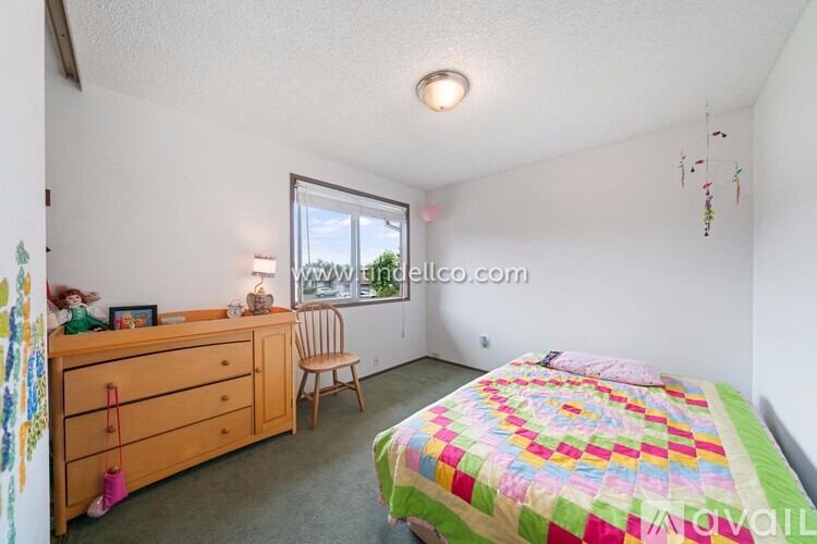 A bedroom with a bed, a chair, a dresser, and a window.