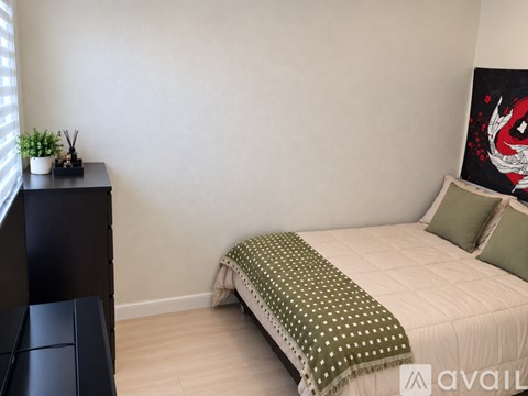 A bedroom with a bed, a nightstand, and a painting on the wall.