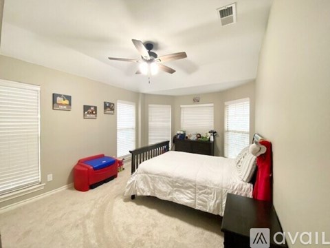 A bedroom with a white bed and a ceiling fan.