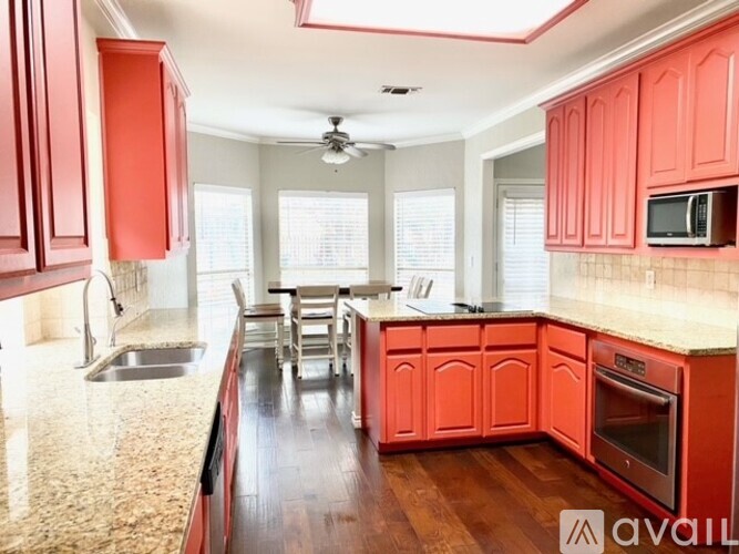 A kitchen with red cabinets and a marble countertop.