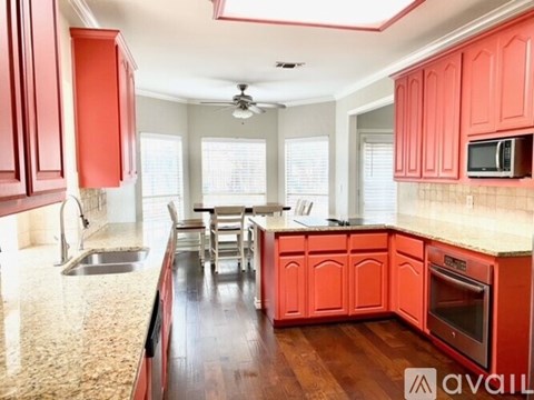 A kitchen with red cabinets and a marble countertop.