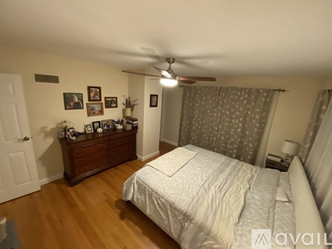 A bedroom with a bed, dresser, and ceiling fan.