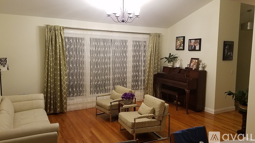 A living room with a piano and a chair with a floral design.