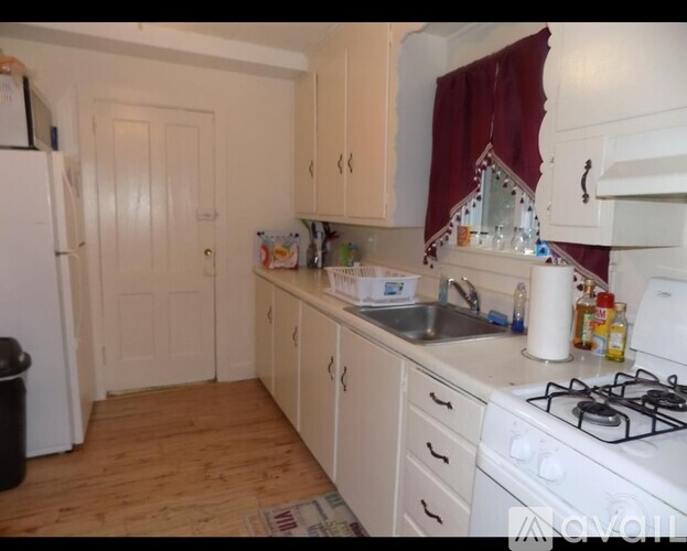 A kitchen with a white gas stove and wooden floors.