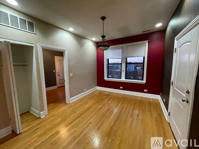 A room with wooden flooring and a window with blinds.
