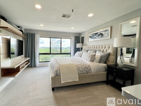 A well-lit bedroom with a large bed and a balcony with a view of the outdoors.