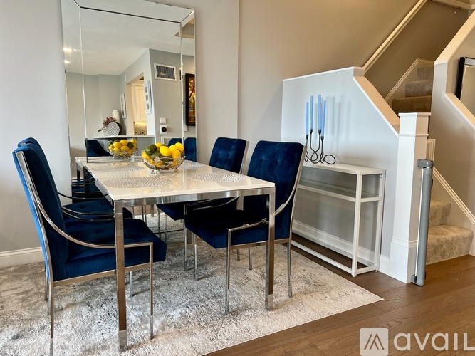A dining room with a glass table and blue chairs.