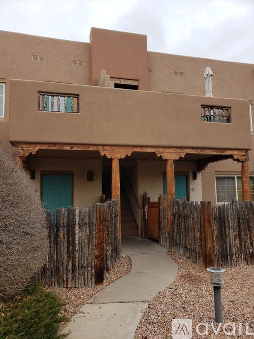 A brown building with a blue door and a wooden fence.