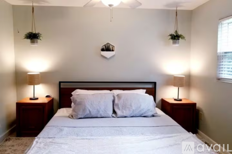 A bedroom with a large bed, two lamps, and a ceiling fan.