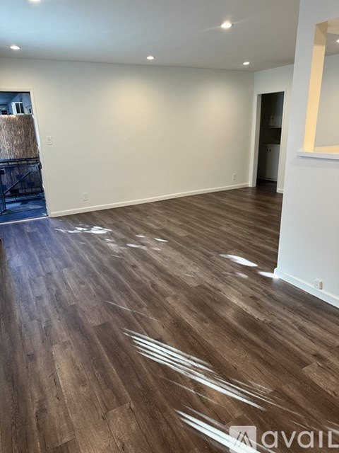 A room with wooden flooring and white walls.
